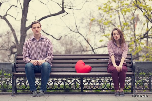 Sad teens sitting at the bench in park