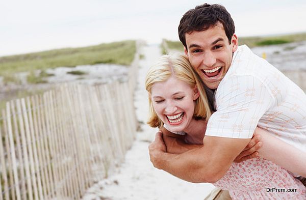 Woman carrying man on her back at beach