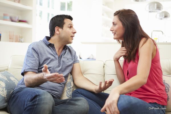 Hispanic Couple Sitting On Sofa Arguing